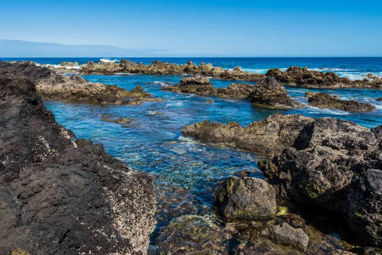 Biscoitos natural pools on Terceira island, with crystal-clear blue water among black volcanic rock formations and the Atlantic Ocean in the background
